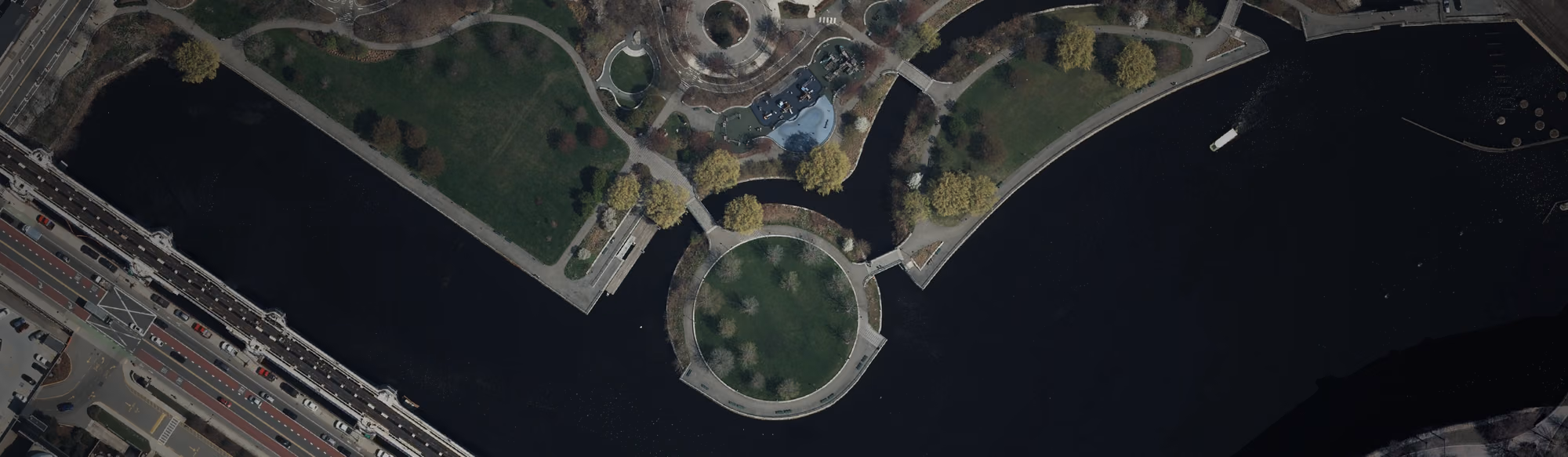 Aerial view of North Point Park in Boston, showing a circular island connected by footbridges and surrounded by the Charles River.